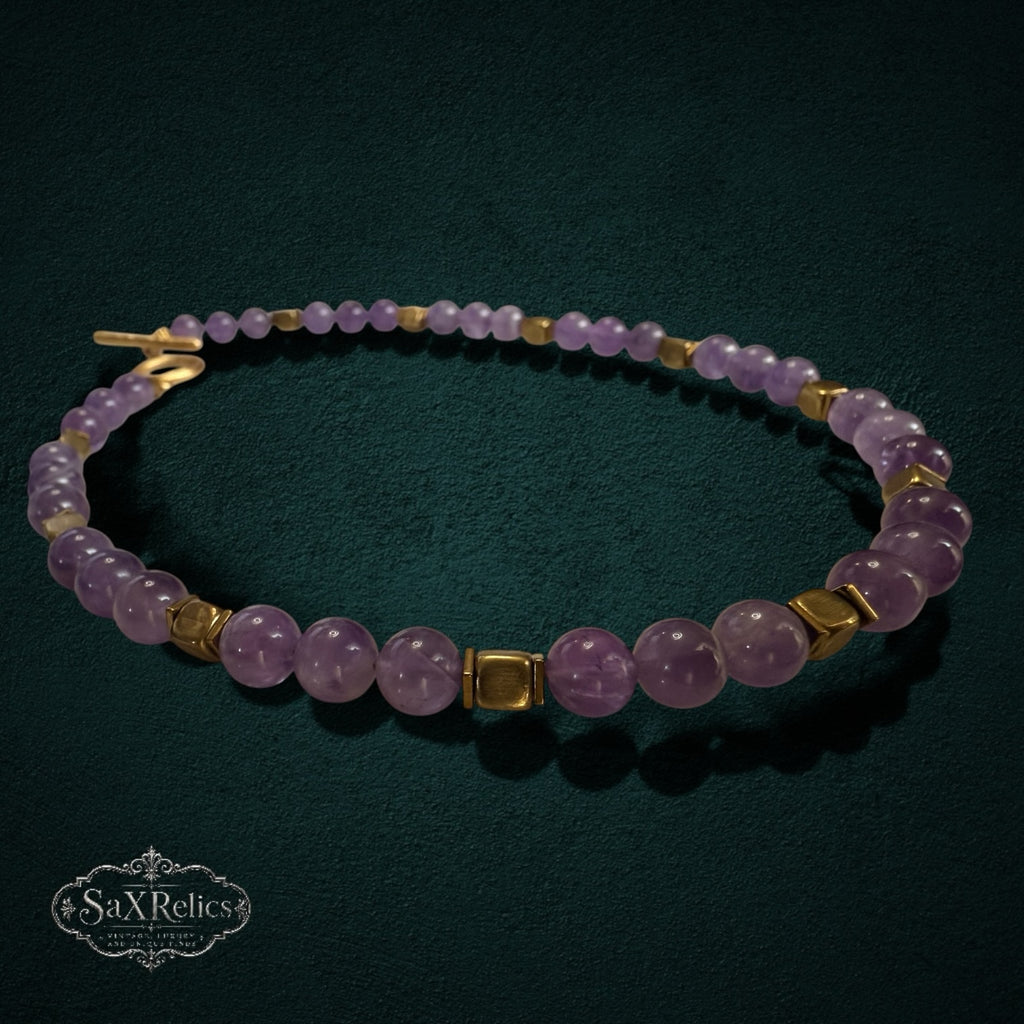 My Store SAXRelics amethyst beaded necklace with gold-tone spacers and a toggle clasp on a dark textured background.