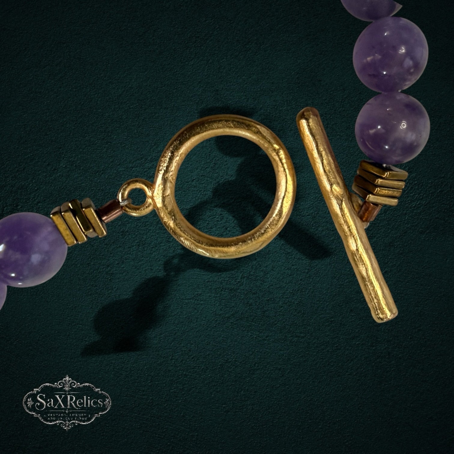 My Store SAXRelics beaded necklace featuring purple amethyst stones and a gold-tone toggle clasp on dark background.