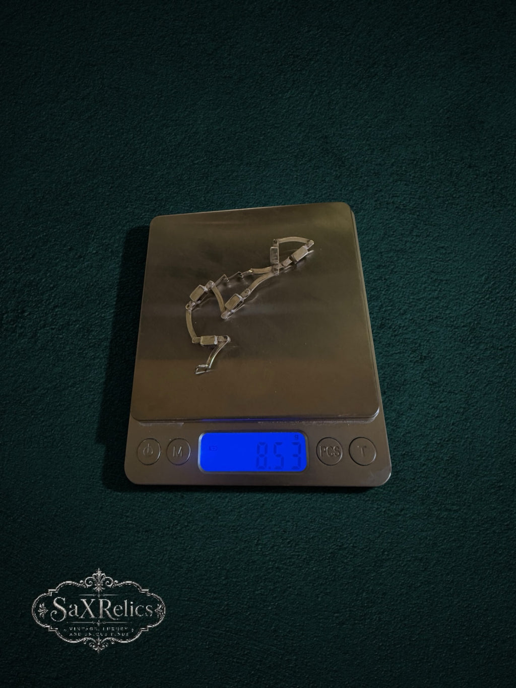 My Store SAXRelics vintage-inspired amethyst link bracelet resting on a digital scale against a dark green background.