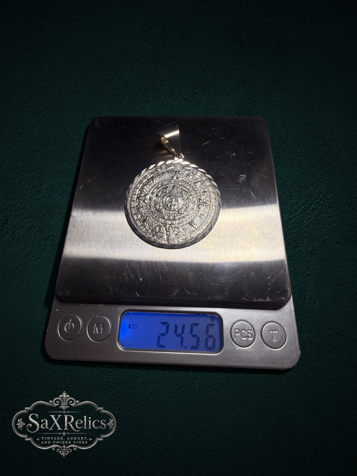 .950 silver Aztec Calendar pendant with intricate embossed detail on a digital scale weighing 24.56 grams.