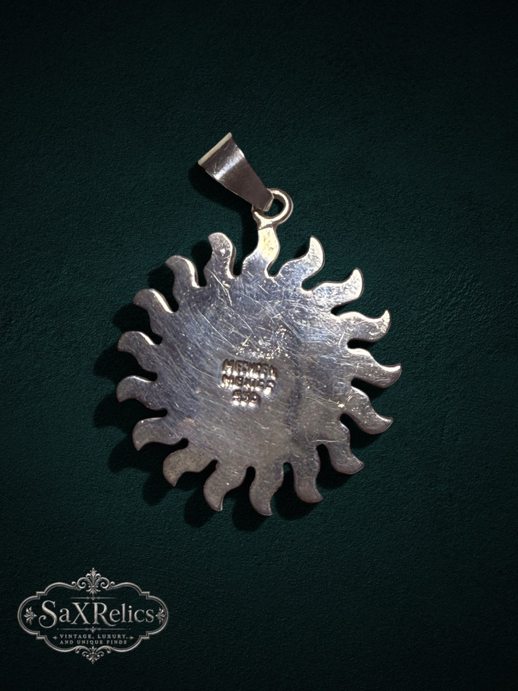 .950 silver Aztec calendar sun pendant with intricate sunburst detailing on a dark background