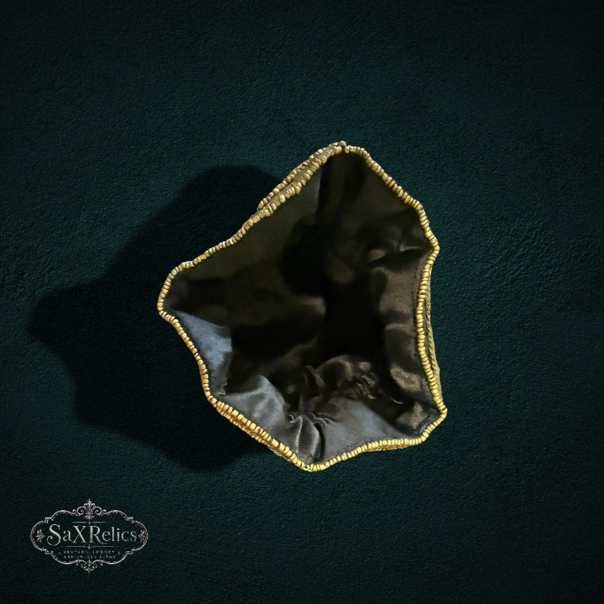 My Store SAXRelics black drawstring pouch with gold beaded trim, viewed from above against a dark background.