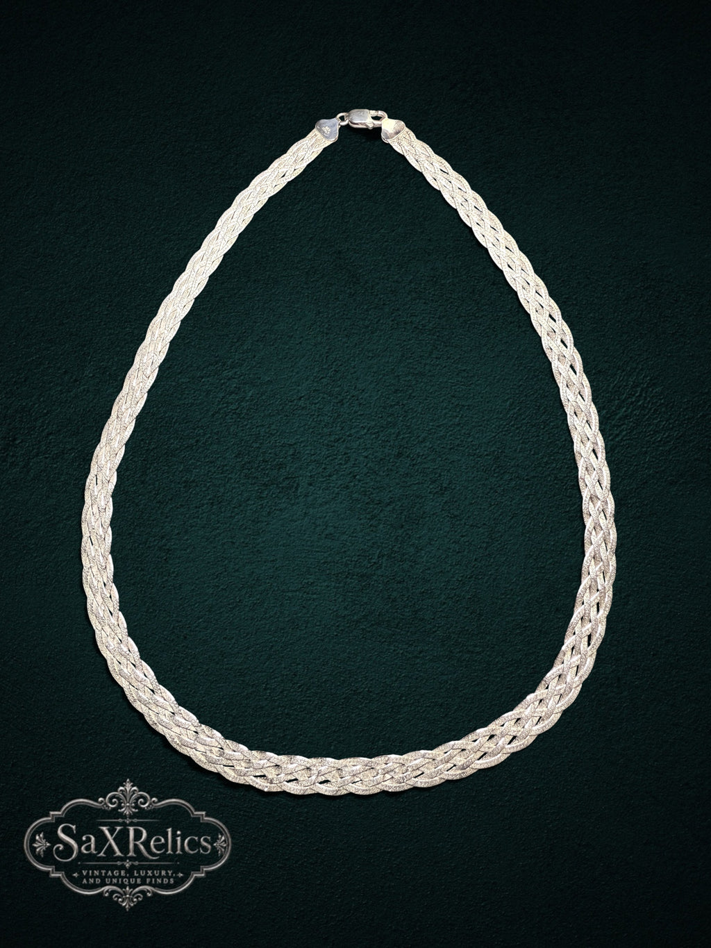 Braided sterling silver multi-strand chain necklace with a textured weave on a dark green background