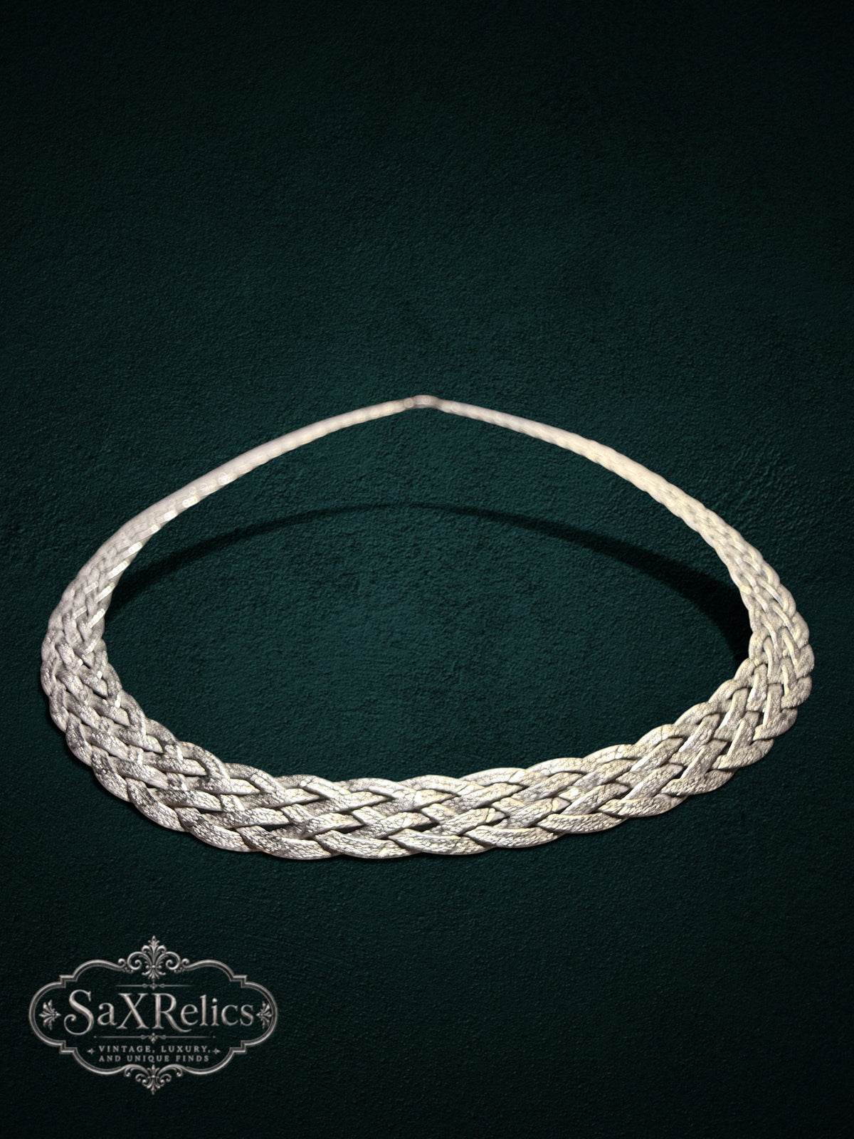 Braided sterling silver chain necklace with an intricate multi-strand weave on a dark green background