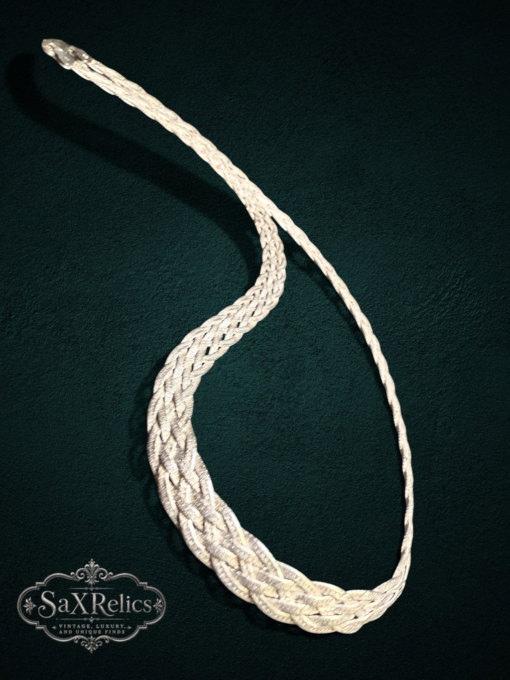 Braided sterling silver chain necklace with a complex multi-strand weave on a dark textured background