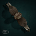 My Store Geneva quartz wristwatch with a dark metallic oval dial, Roman numerals, and a textured fan-like mesh bracelet.