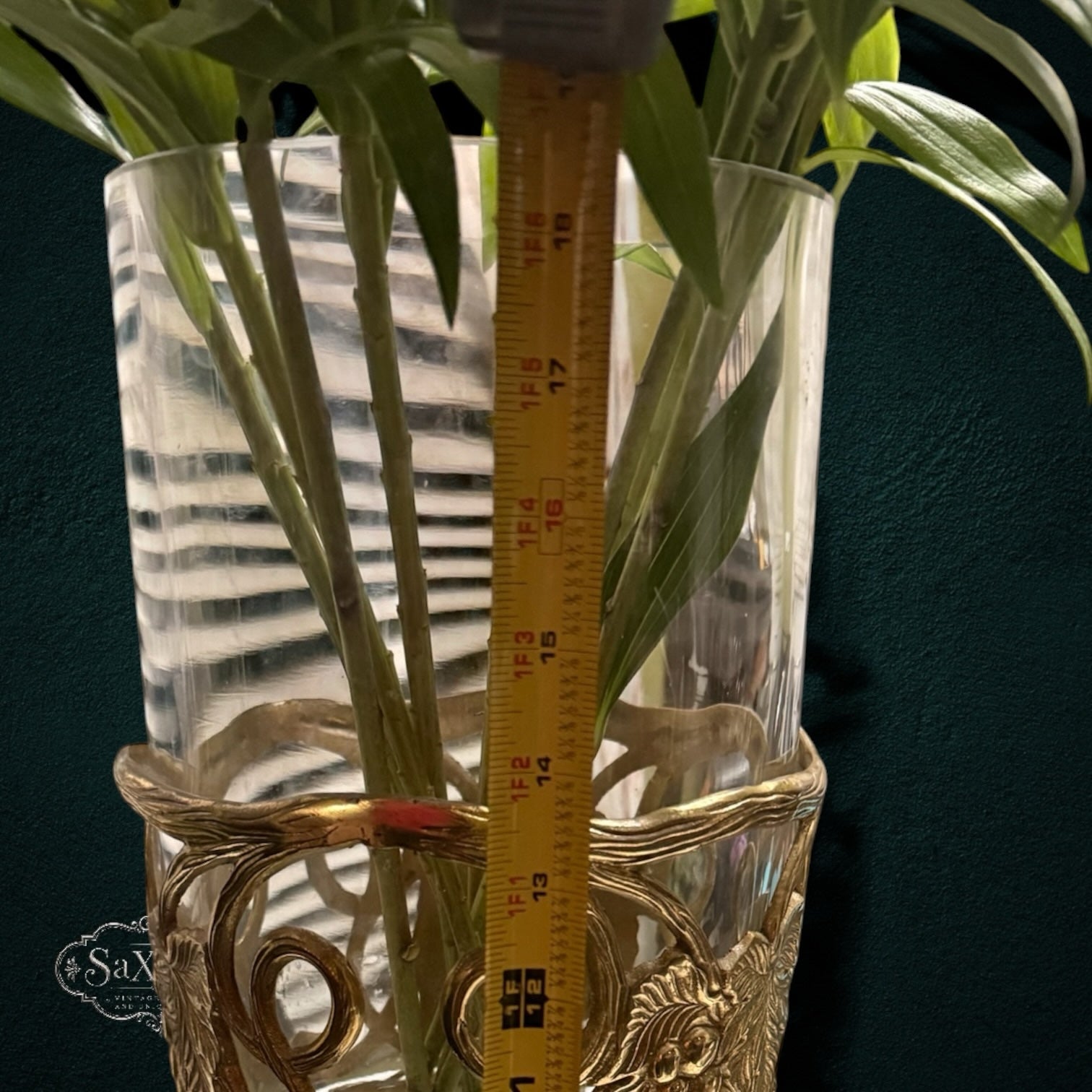 My Store SAXRelics glass flower vase in an ornate brass-tone metal stand with vine motifs and a measuring tape inside.