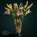 My Store SAXRelics glass flower vase in an ornate brass-tone metal stand with grape and vine motifs holding lilies.