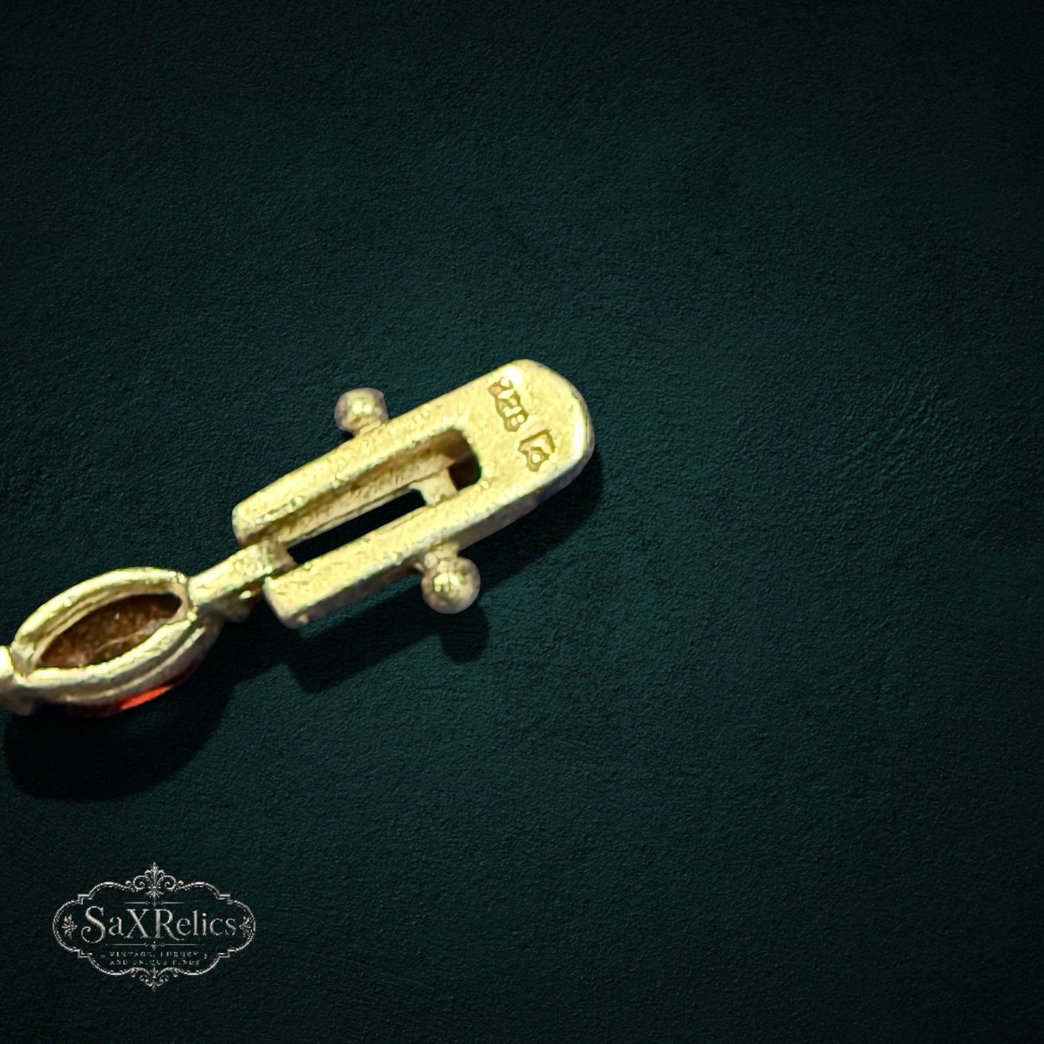 My Store gold bracelet clasp with hallmark detail and a marquise-cut gemstone link on a dark textured background