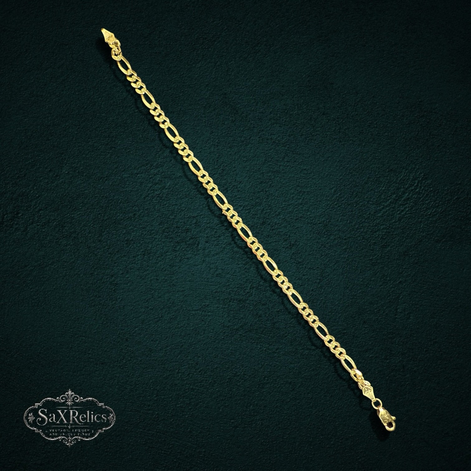 SaX Relics sterling silver Figaro chain bracelet with alternating oval and circular links on a dark textured background