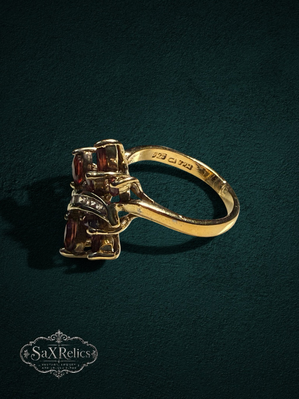 My Store vintage-inspired gold statement ring with marquise-cut red garnet stones and clear accent gems on dark background