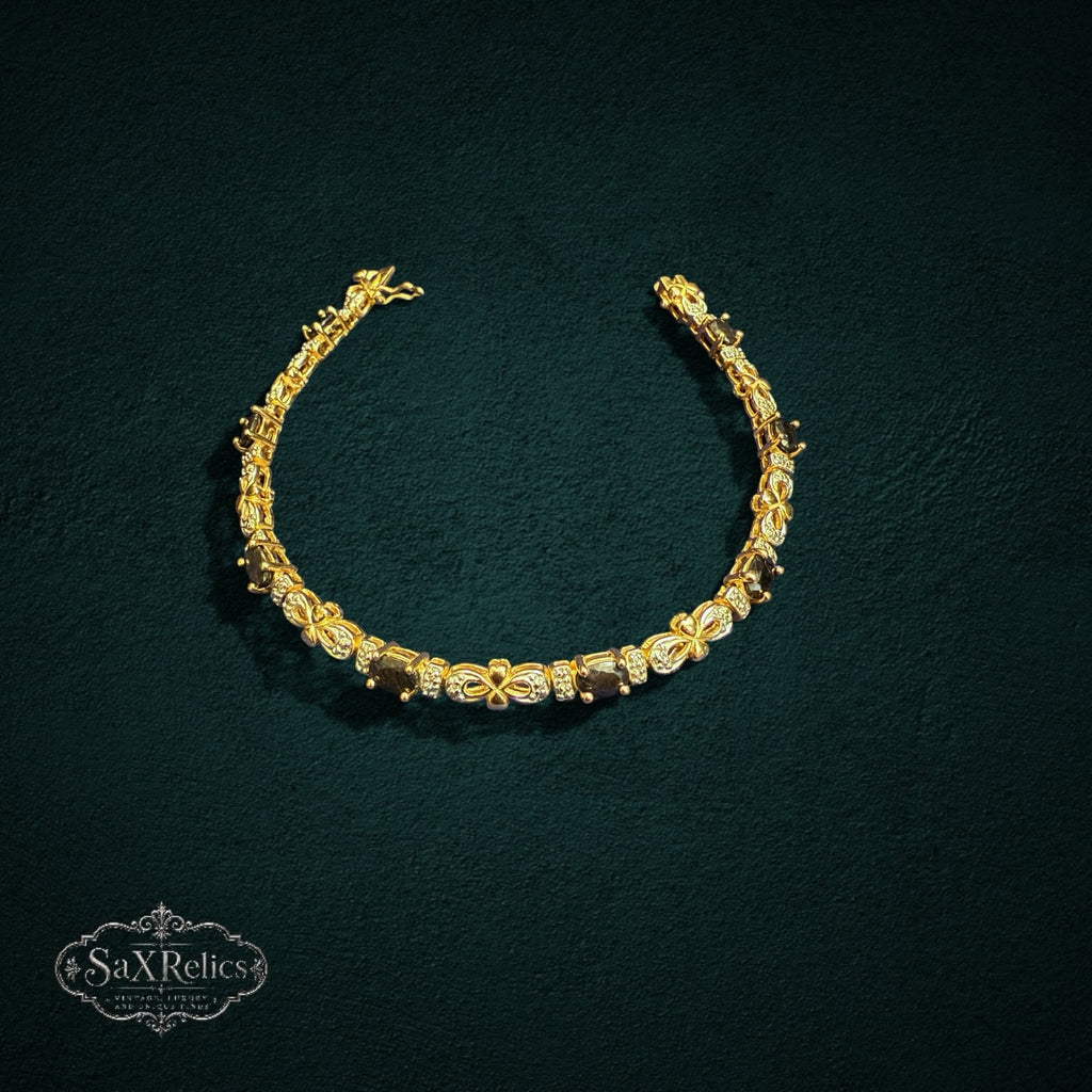 My Store SAXRelics gold-toned link bracelet with oval gemstones and pave-set stones on a dark textured background.