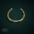 My Store SAXRelics gold-toned link bracelet with oval gemstones and pave-set stones on a dark textured background.
