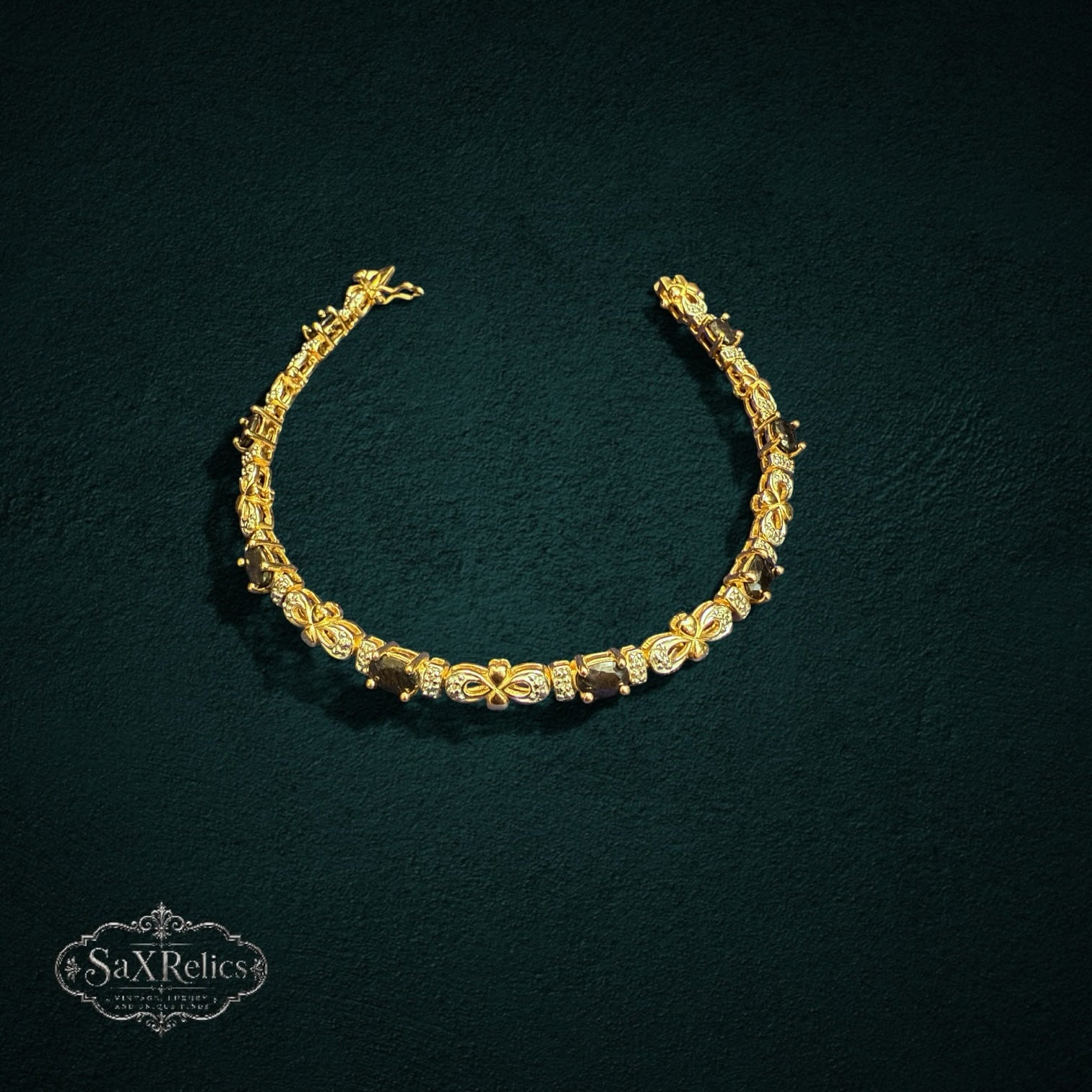 My Store SAXRelics gold-toned link bracelet with oval gemstones and pave-set stones on a dark textured background.