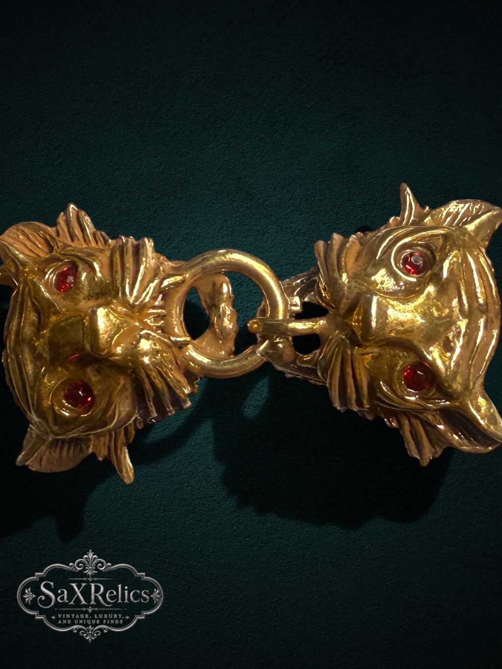 SaX Relics gold-tone lion head link bracelet with vibrant red gemstone eyes on a dark textured background
