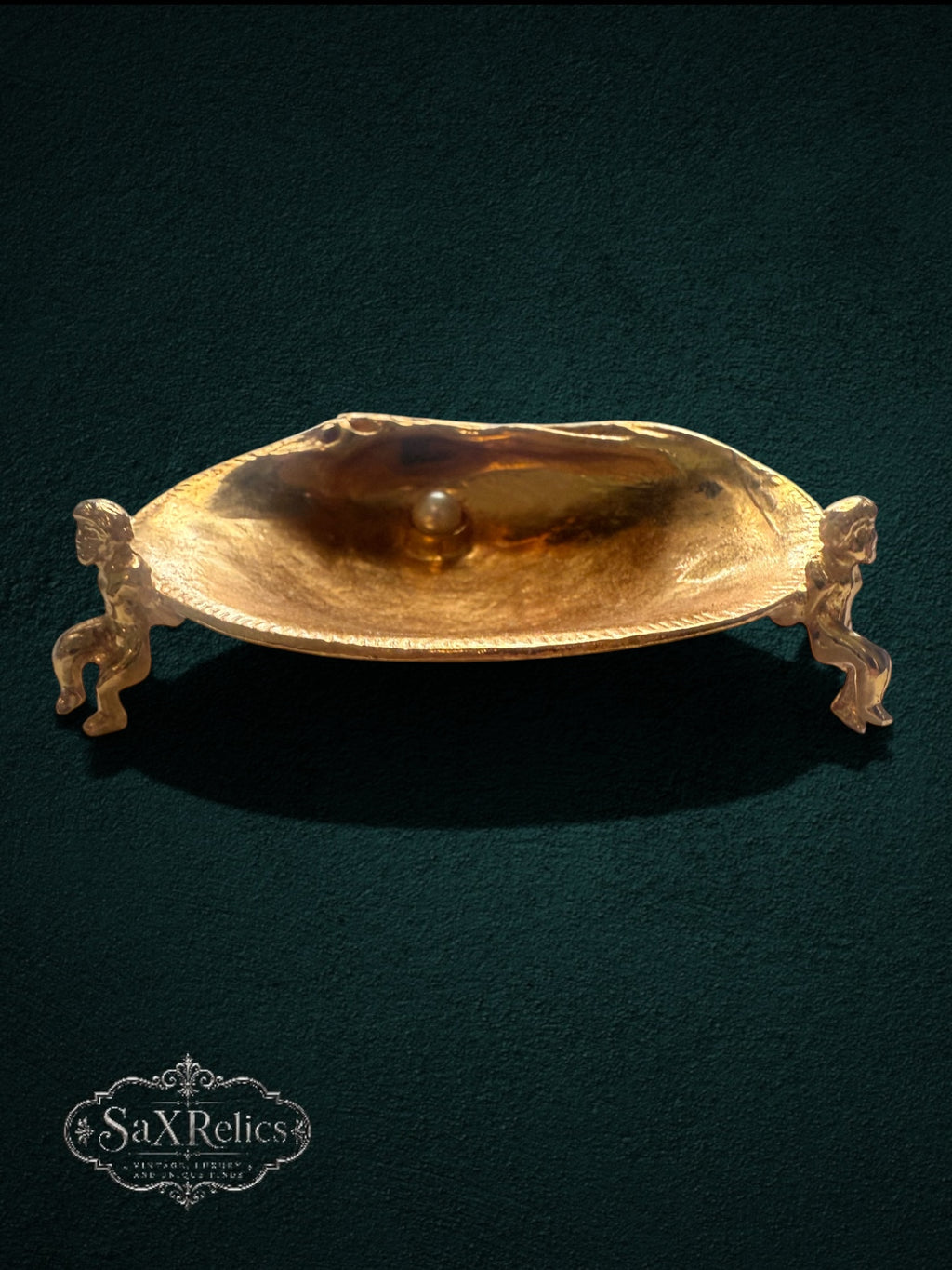 My Store gold-tone shell trinket dish featuring two cherub figures and a faux pearl on a dark green background