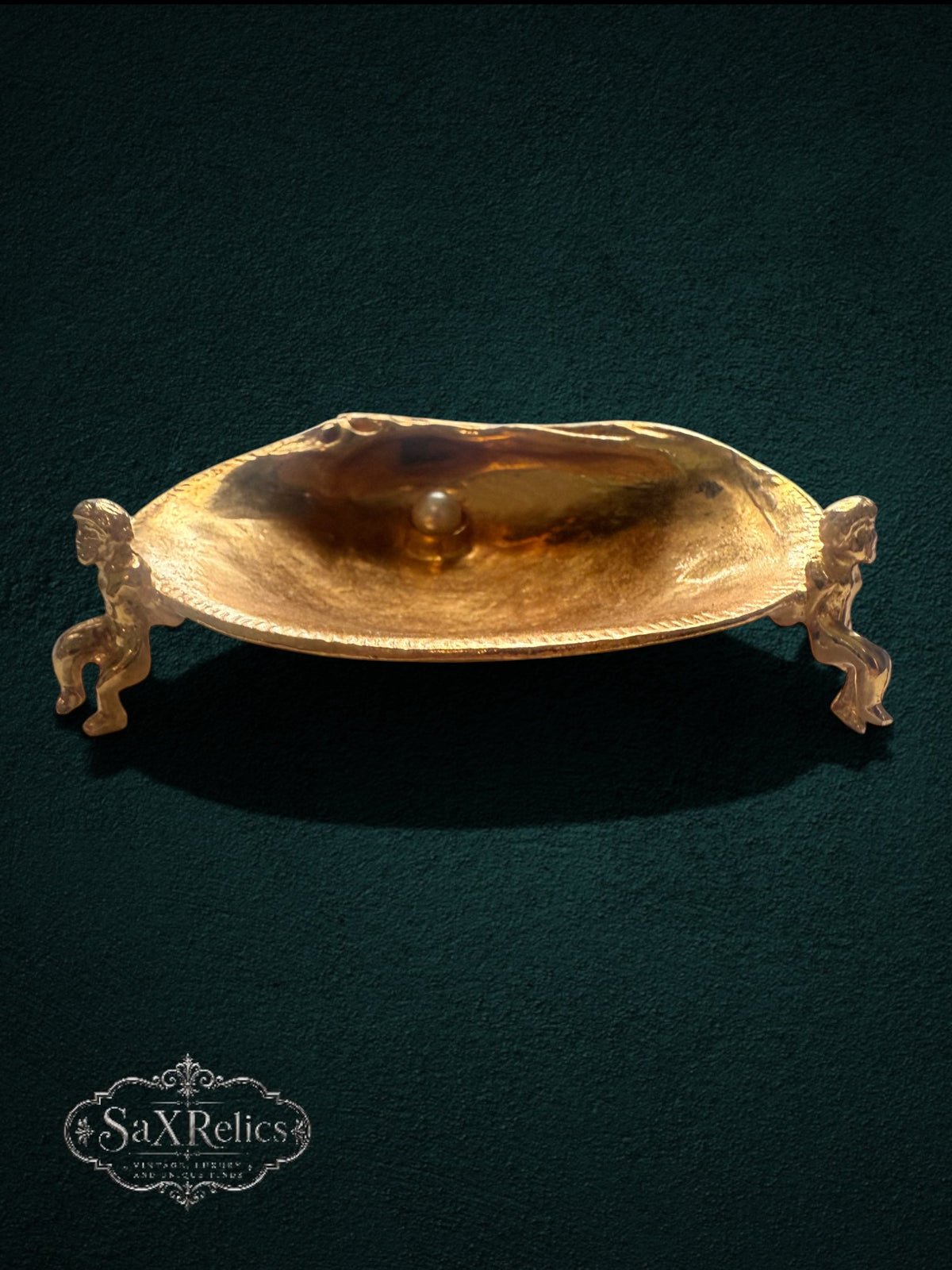 My Store gold-tone shell trinket dish featuring two cherub figures and a faux pearl on a dark green background