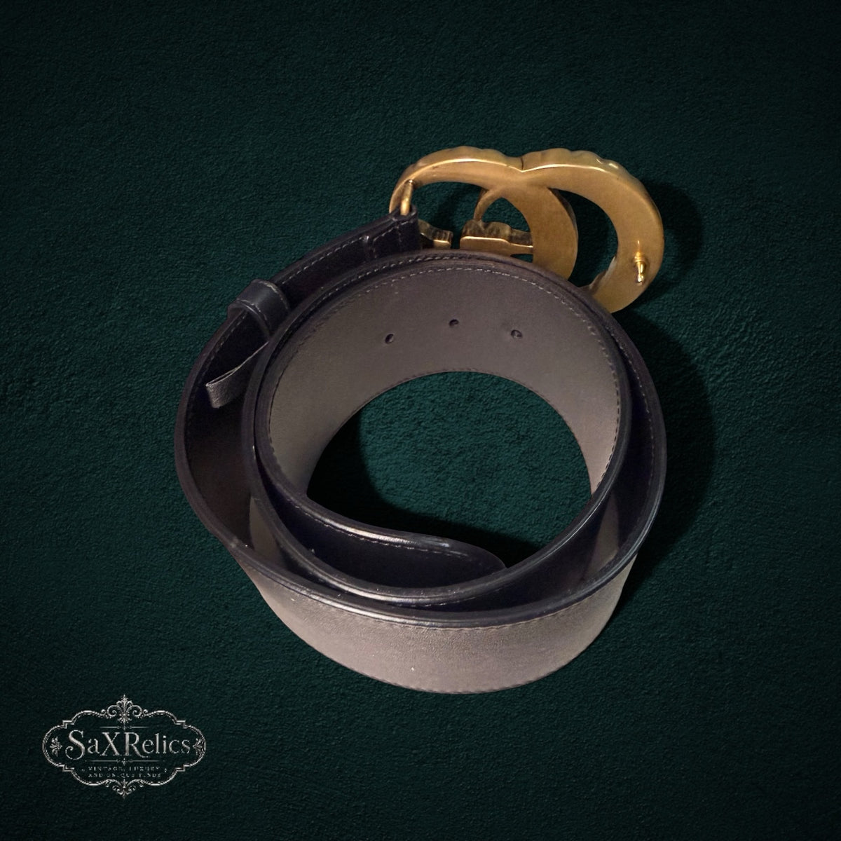 My Store Gucci black leather belt featuring an iconic antique-gold Double G buckle on a dark textured background.