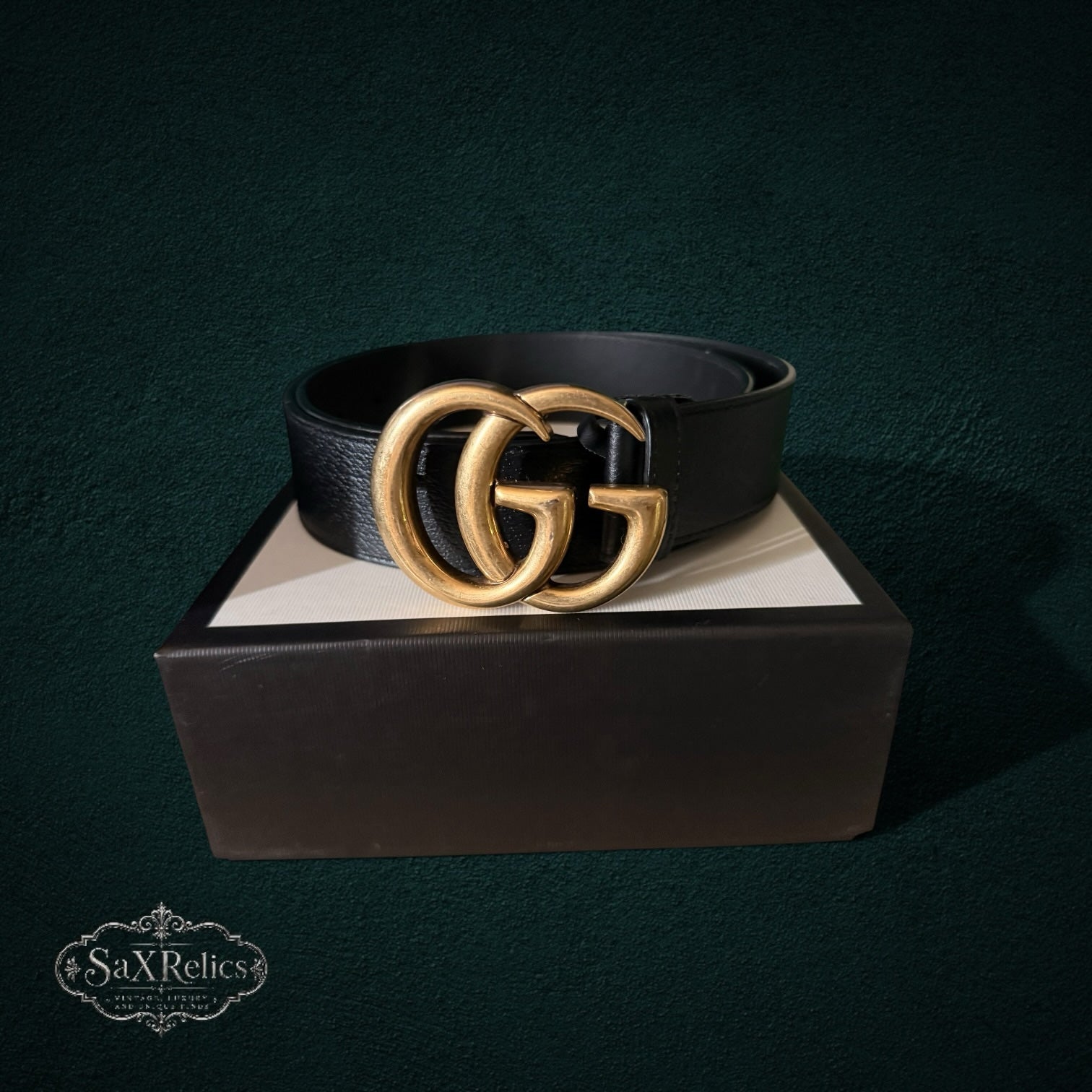 My Store GUCCI black leather belt with an antique gold interlocking GG buckle resting on a branded luxury box
