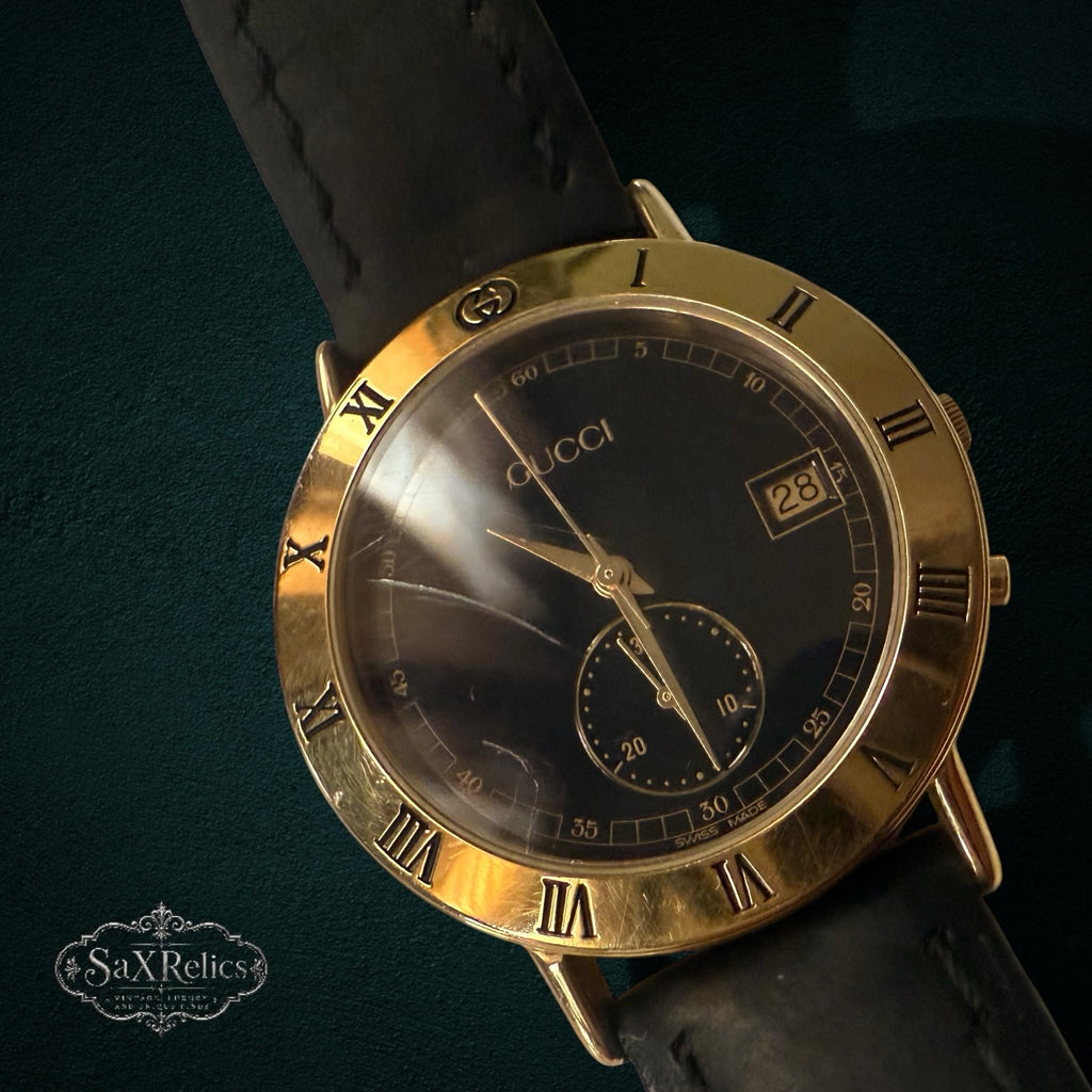 My Store vintage Gucci analog wristwatch with a gold-tone Roman numeral bezel, black dial, and black leather strap.