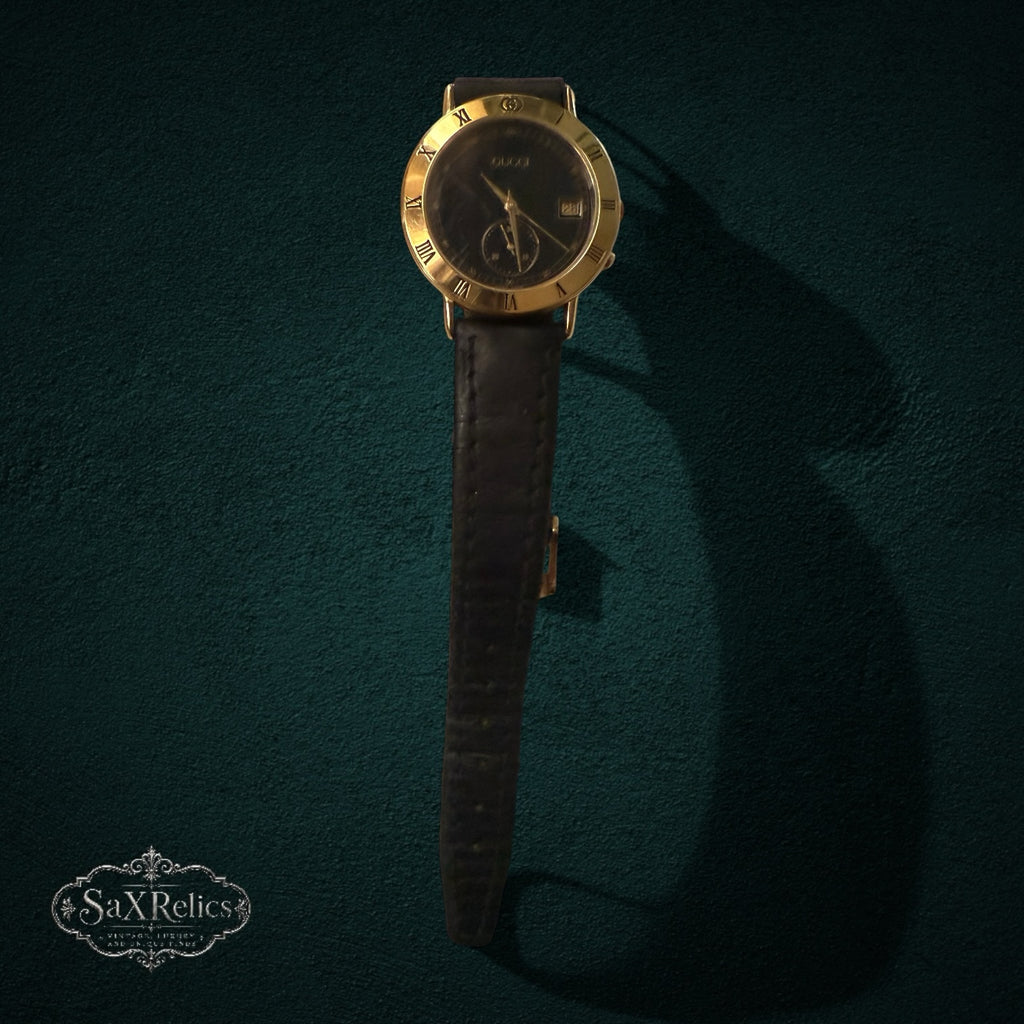 My Store vintage Gucci analog watch with gold-tone Roman numeral bezel, black dial, and black leather strap.