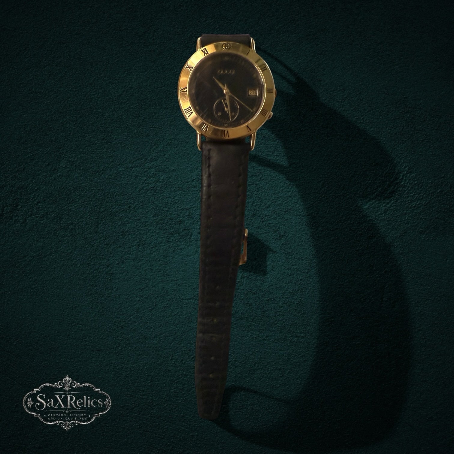 My Store vintage Gucci analog watch with gold-tone Roman numeral bezel, black dial, and black leather strap.