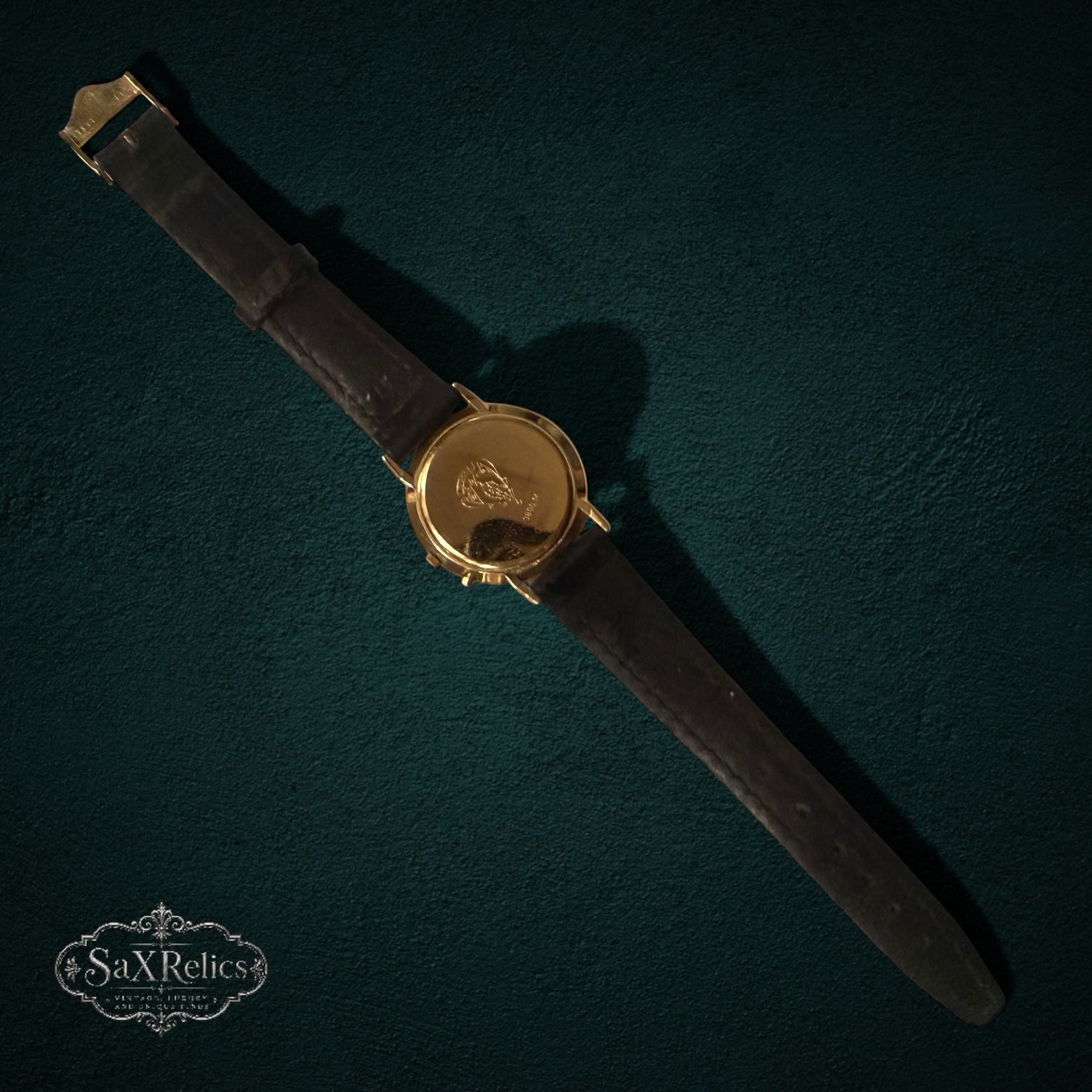 My Store vintage Gucci analog wristwatch featuring a gold-tone case back and a black leather strap on a dark background.