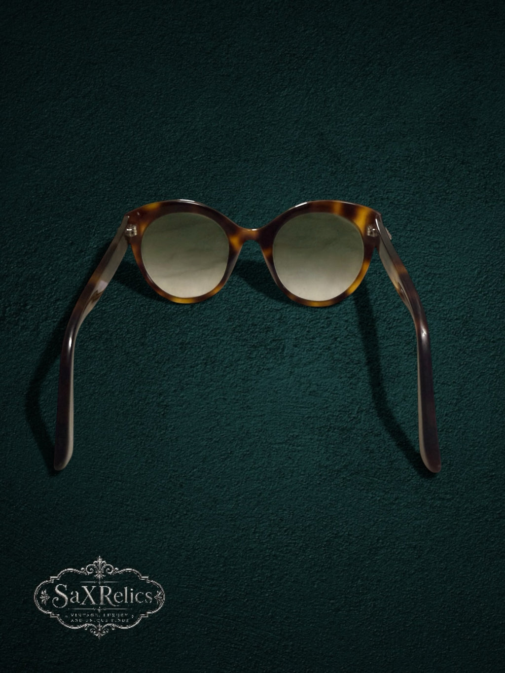 My Store Gucci tortoiseshell cat-eye sunglasses with gradient lenses on a dark green textured background