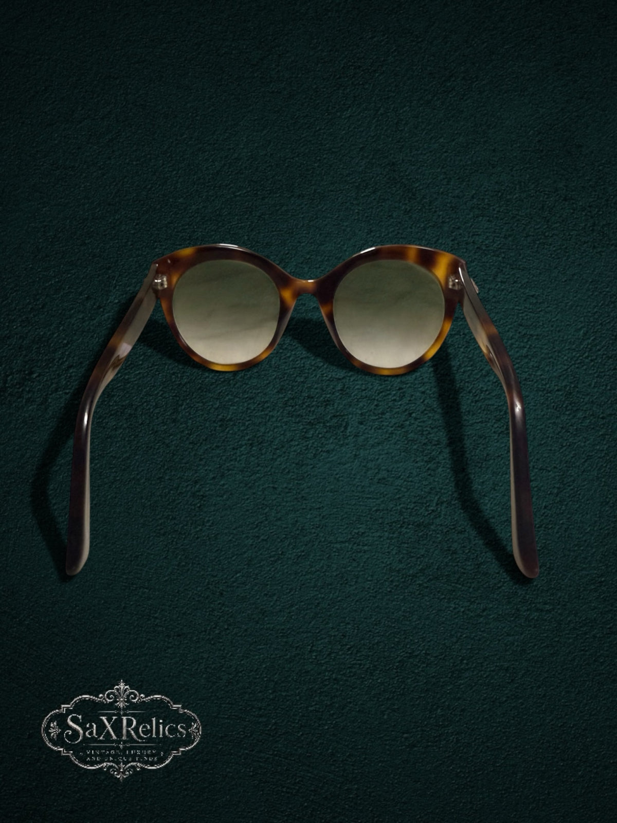 My Store Gucci tortoiseshell cat-eye sunglasses with gradient lenses on a dark green textured background