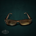 My Store vintage Gucci sunglasses in warm brown Optyl with crystal logo detail on temples, shown on dark green background.