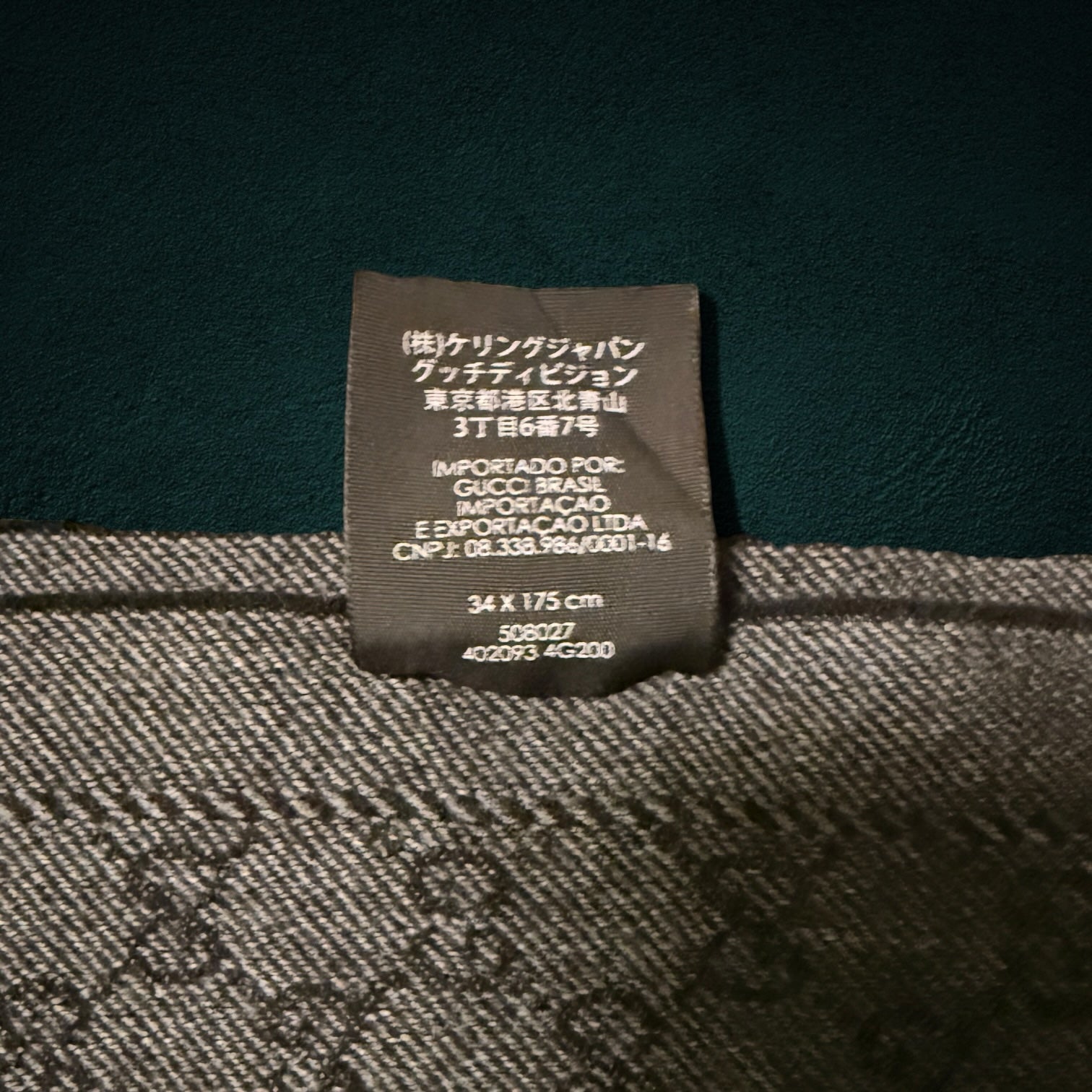 My Store Gucci wool scarf featuring the iconic GG monogram pattern and a detailed product care label in grey and charcoal.