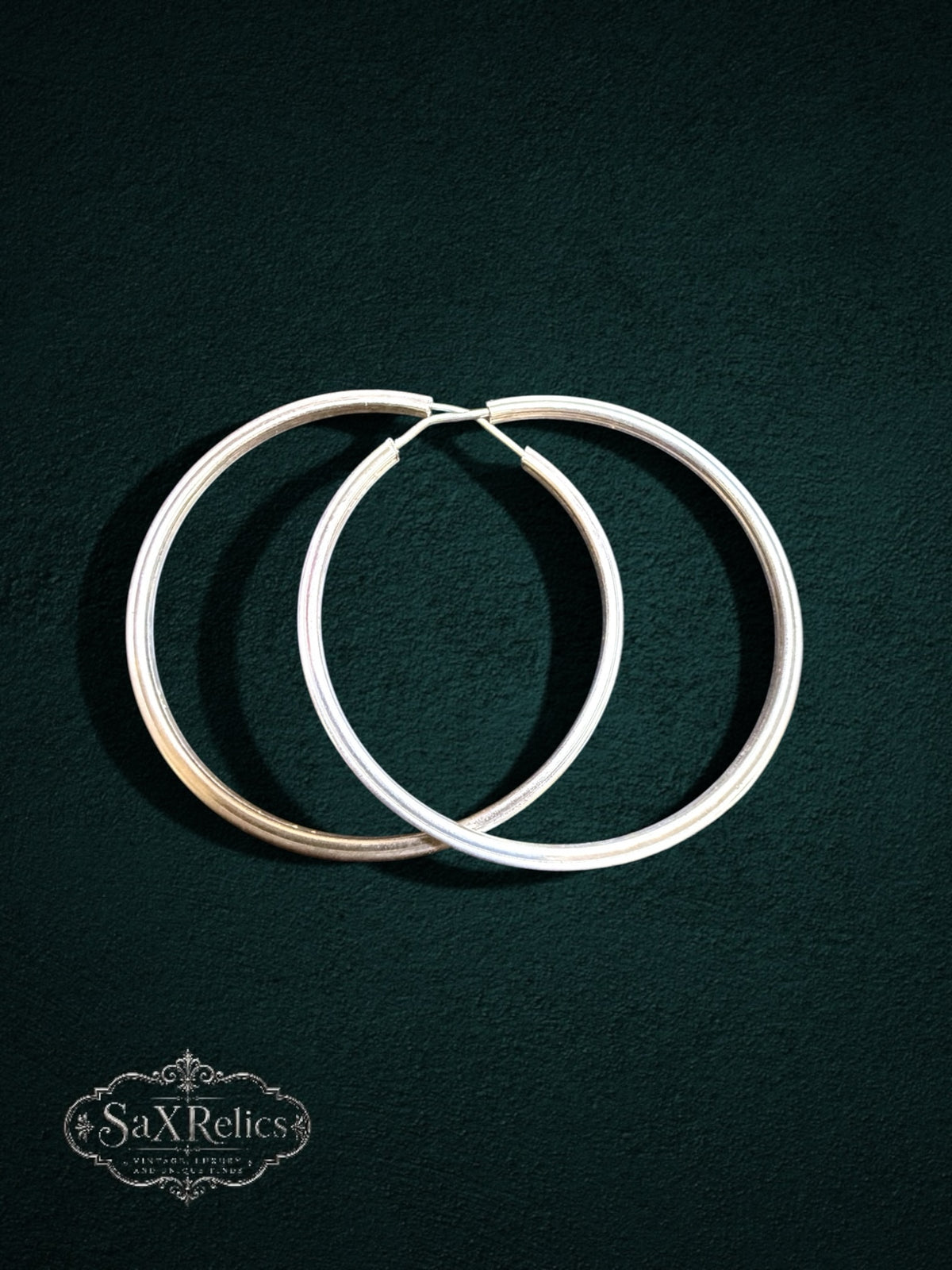 My Store SaxRelics large sterling silver hoop earrings with a delicate textured pattern on a dark background