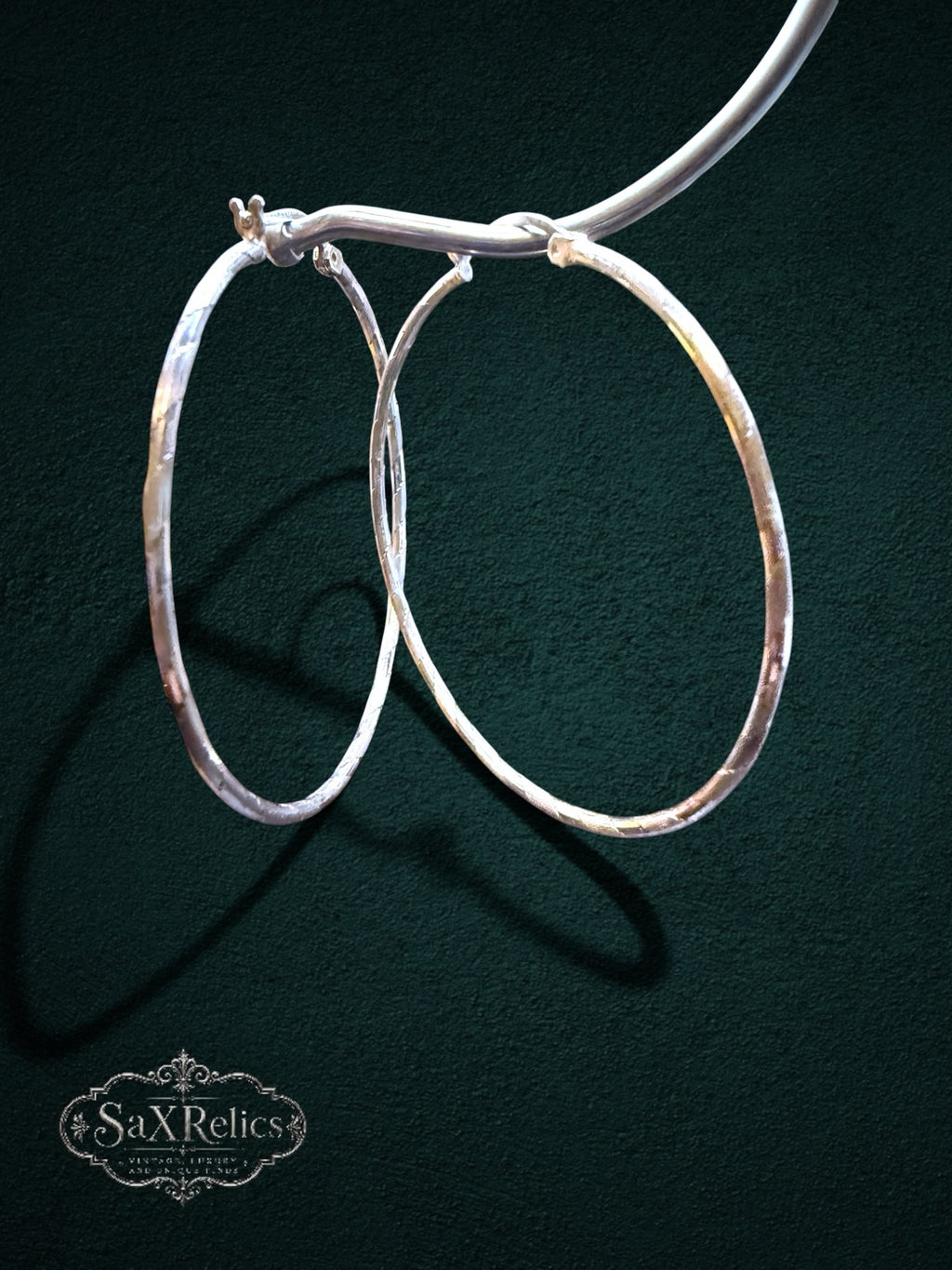 My Store large sterling silver hoop earrings with a textured finish and secure hinged closure on a dark background.