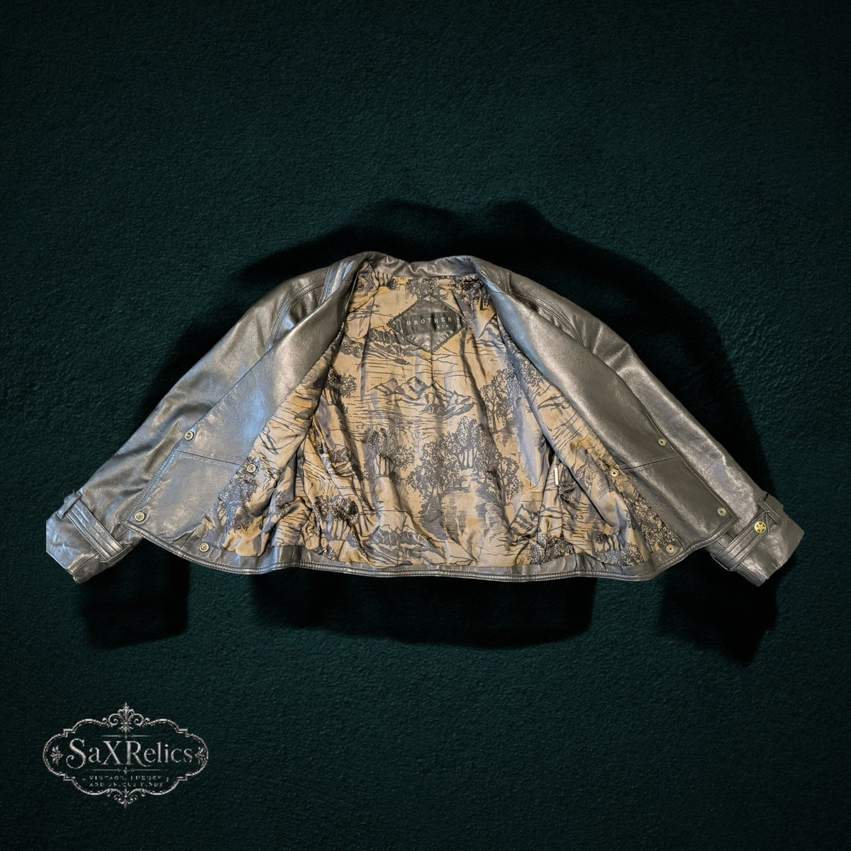 BROTHERS metallic silver leather jacket with double-breasted design and artistic landscape print lining.