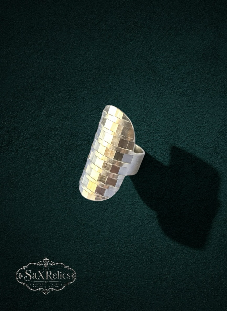 My Store modern silver statement ring with an elongated silhouette and a textured grid pattern on a dark background.