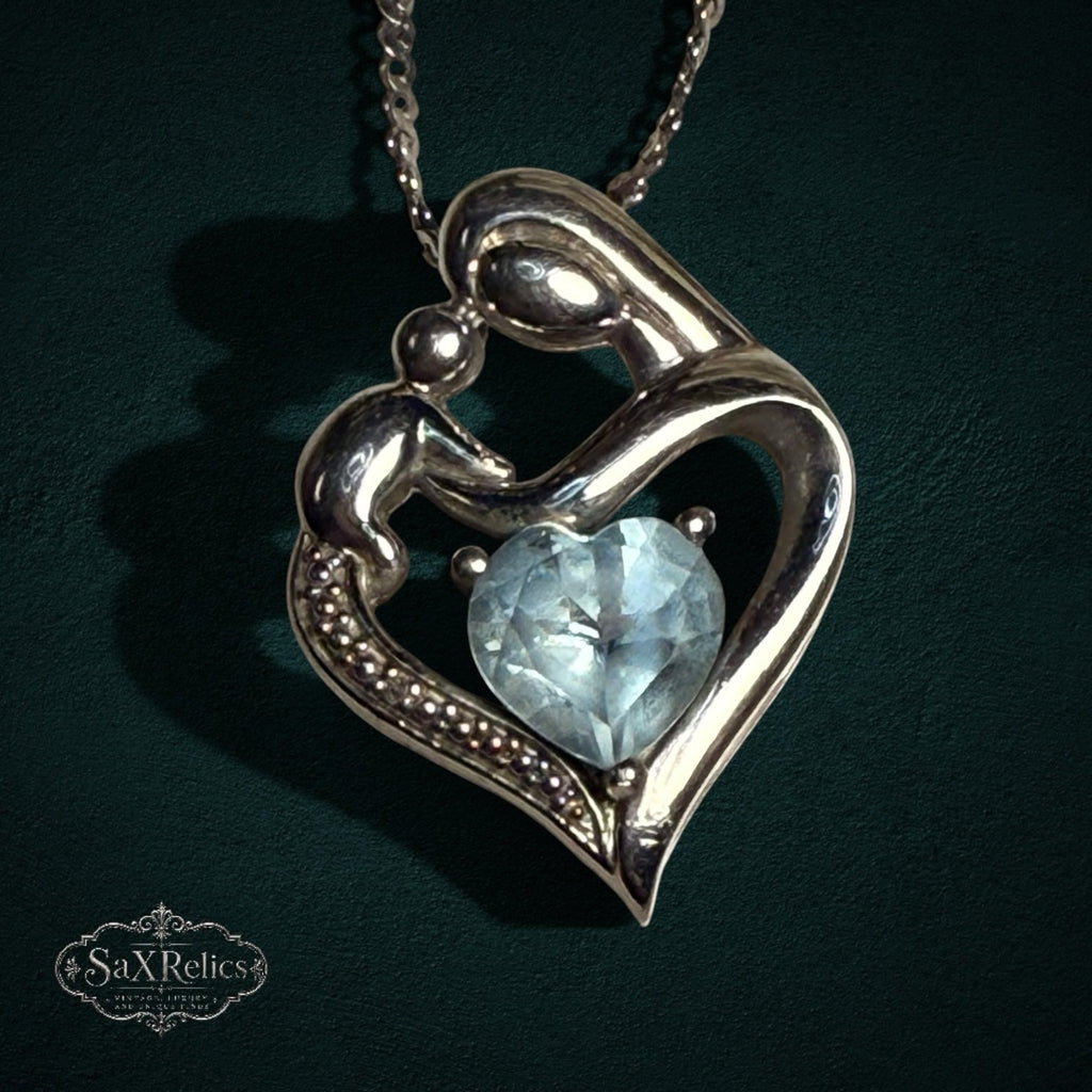 My Store sterling silver mother and child heart pendant necklace with a light blue heart-cut gemstone on a silver chain.