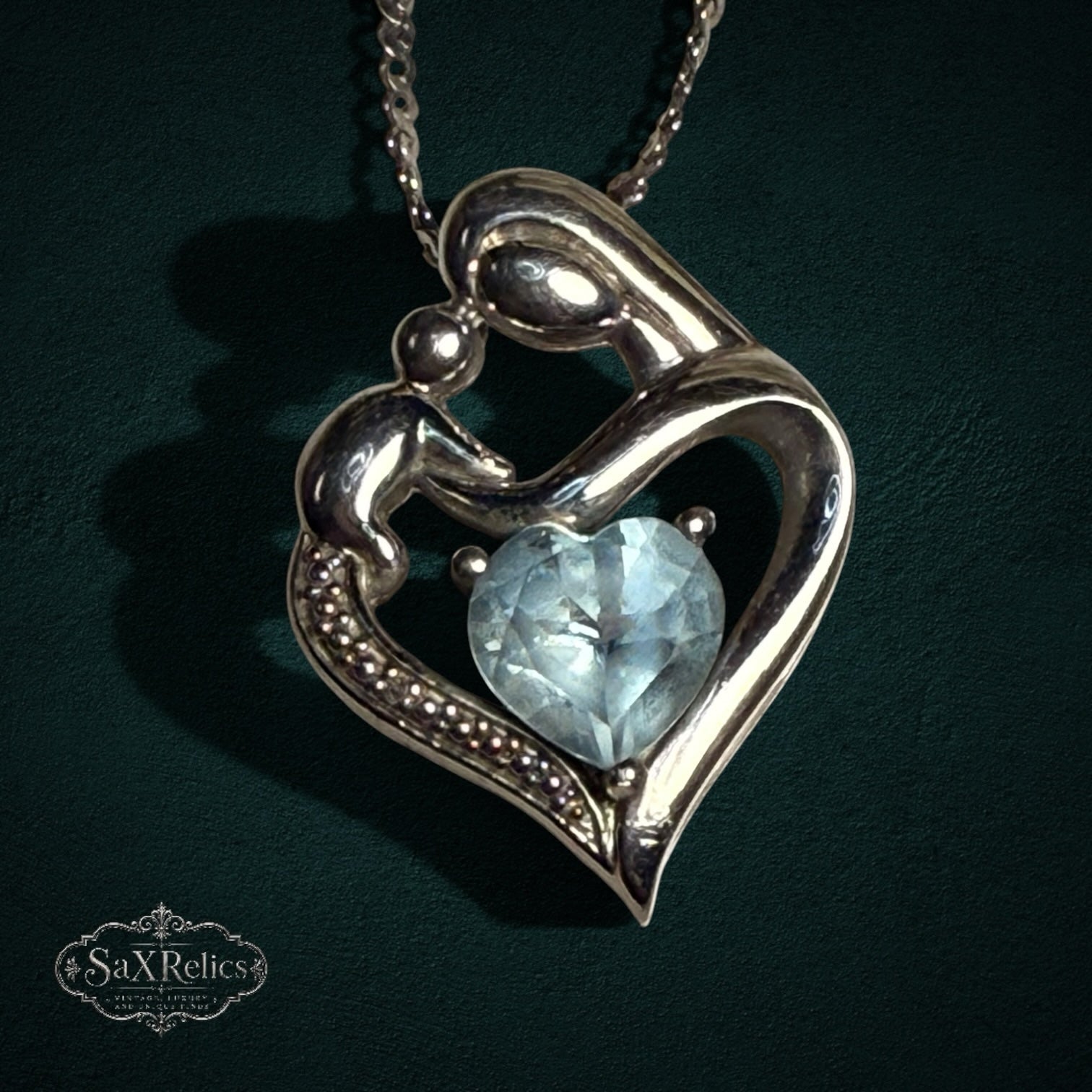My Store sterling silver mother and child heart pendant necklace with a light blue heart-cut gemstone on a silver chain.