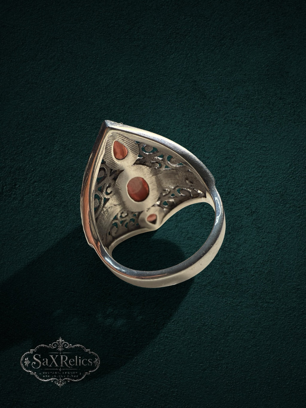 My Store SAXRelics ornate silver filigree statement ring with three earthy cabochon stones on a dark green background.