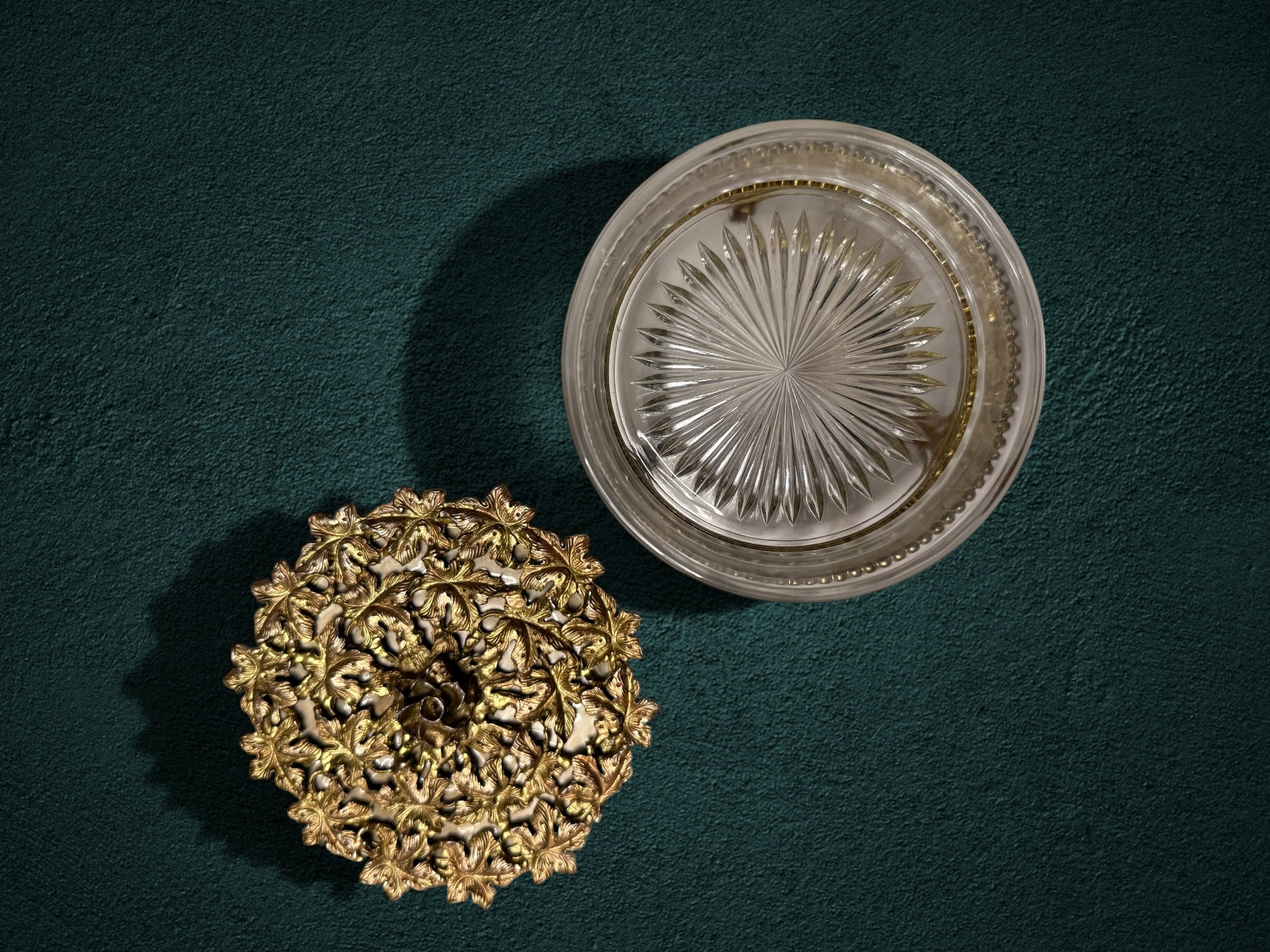 My Store ornate gold metal and faceted glass trinket box with floral lid, top view on a dark green textured surface.