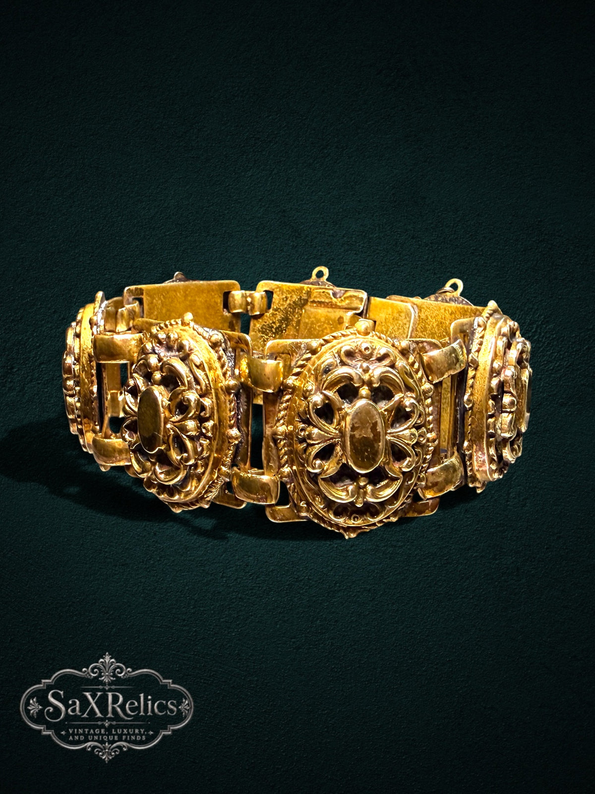 Ornate vintage-style gold-tone link bracelet with intricate filigree scrollwork and oval-shaped links.