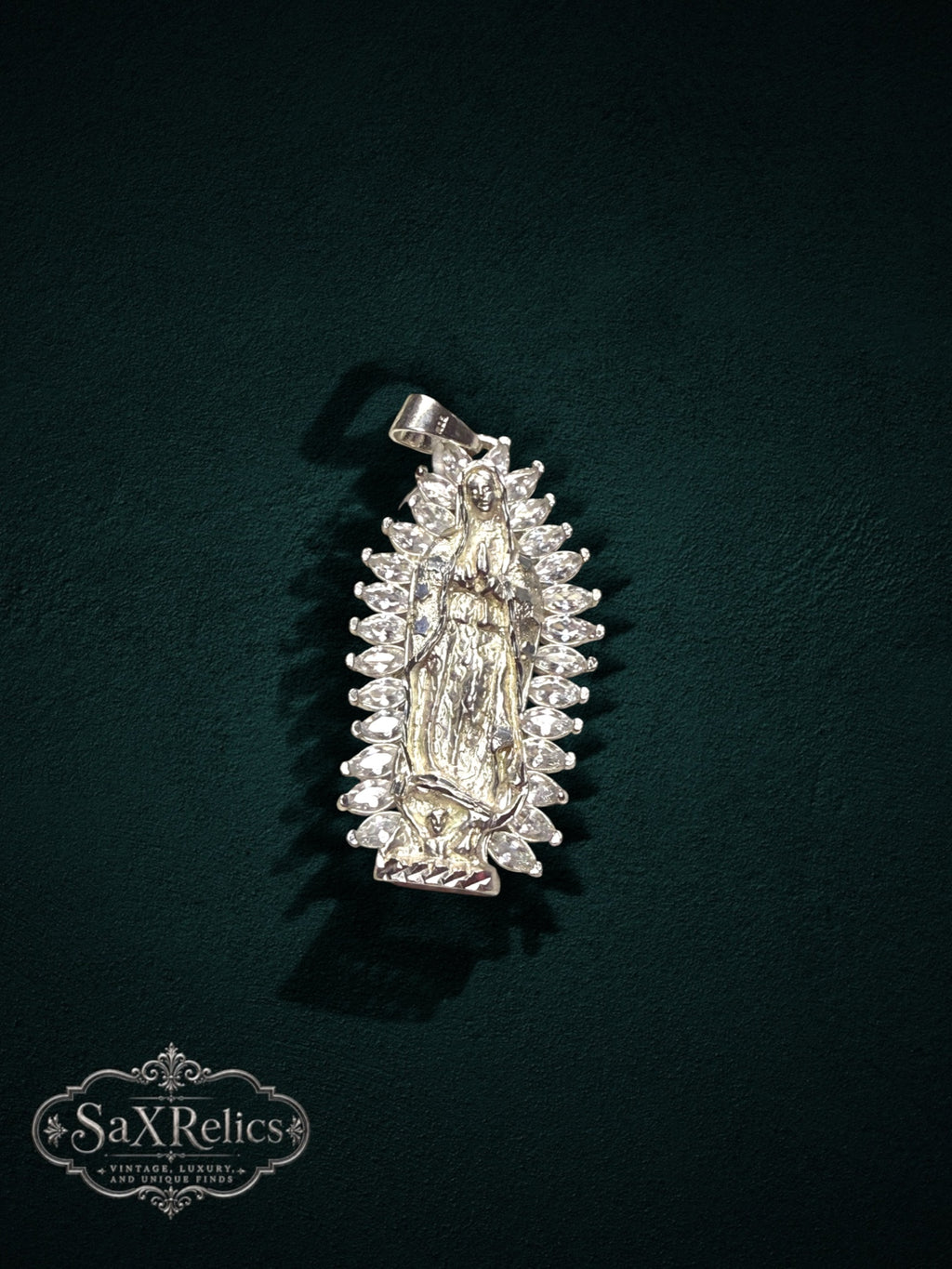 My Store Our Lady of Guadalupe silver-tone pendant with a halo of marquise-cut stones on a dark green background.