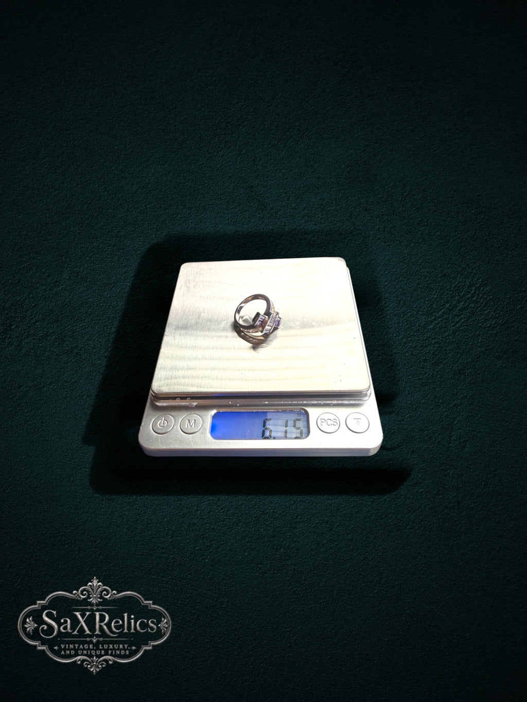 My Store statement ring with purple baguette-cut stones on a digital scale against a dark green background