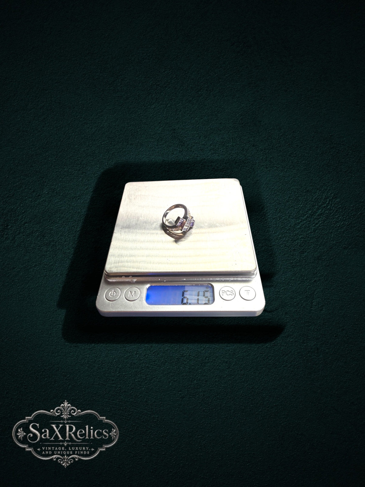 My Store statement ring with purple baguette-cut stones on a digital scale against a dark green background
