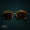 My Store Ray-Ban polarized sunglasses with a gold-tone geometric metal frame on a dark green textured background.