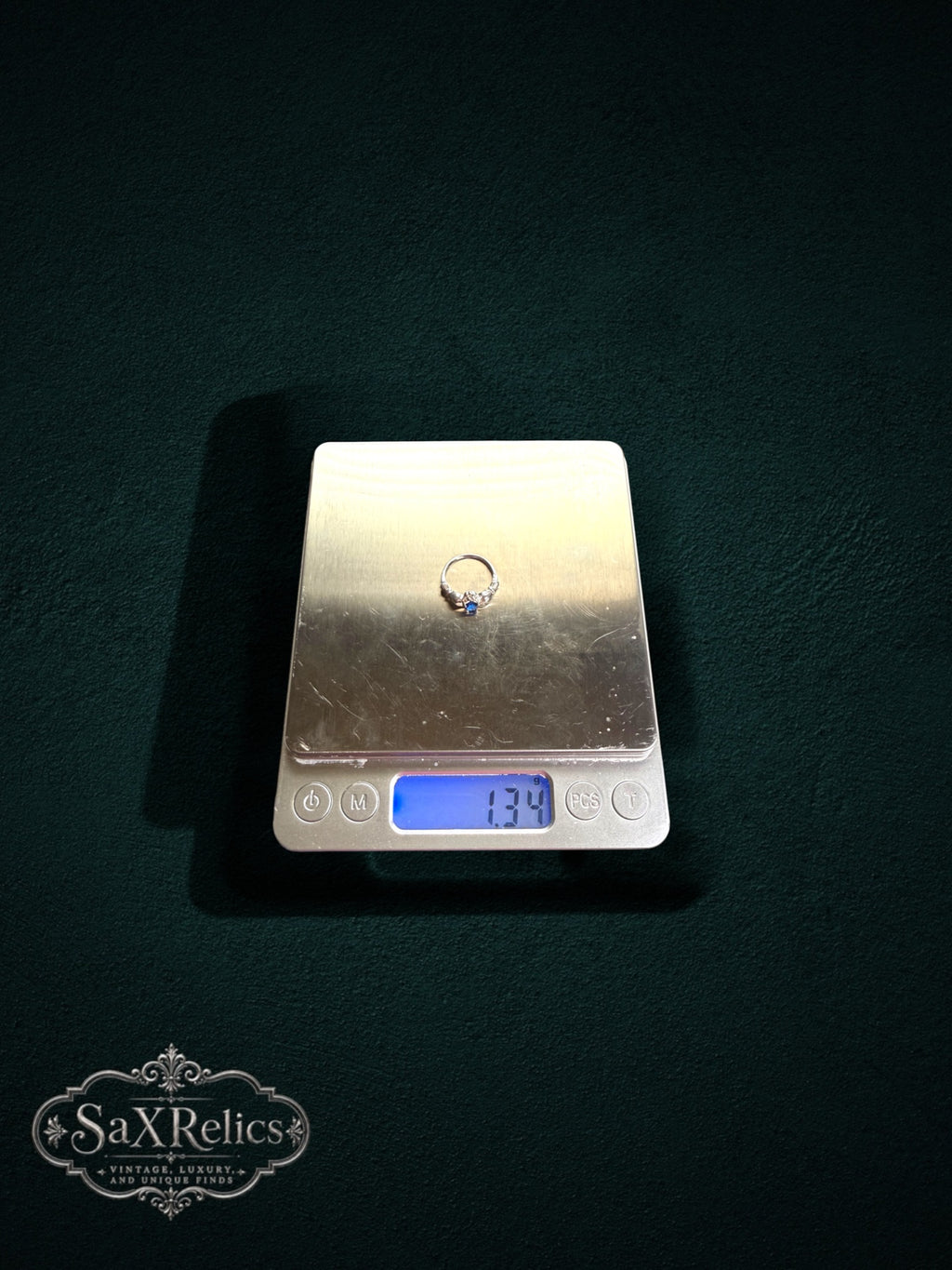 My Store SAXRelics sterling silver Claddagh ring with a blue stone being weighed on a digital scale