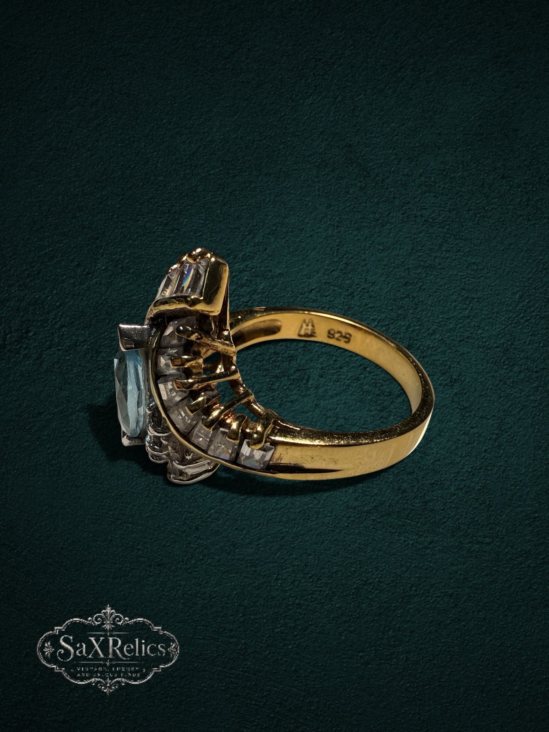 My Store SaxRelics statement ring with a marquise aquamarine stone, baguette accents, and a gold-tone band side view.