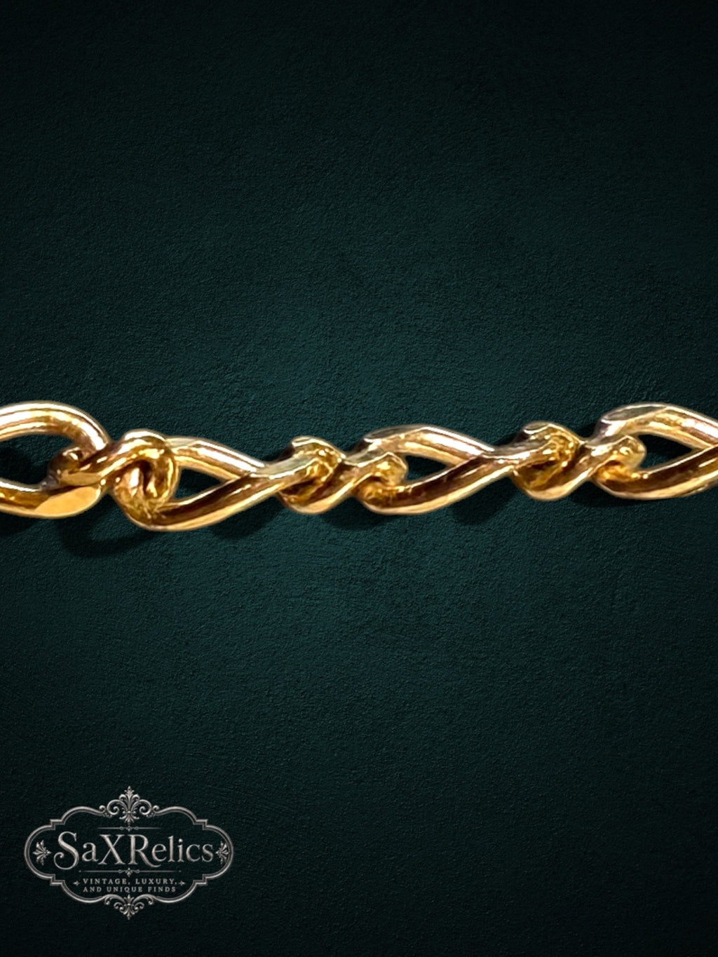 SaX Relics gold-tone decorative link bracelet with an intricate twisted chain design on a dark background.