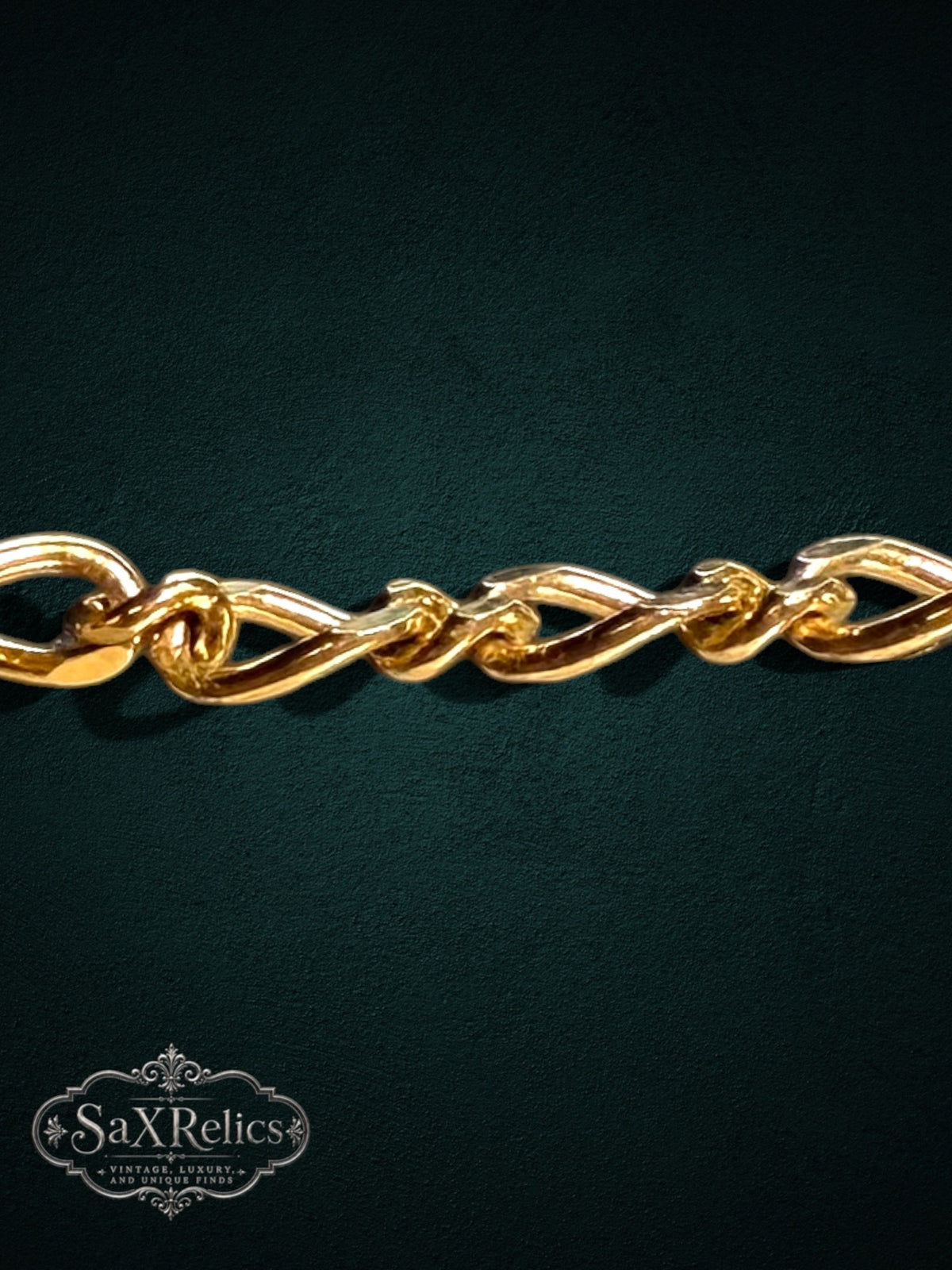 SaX Relics gold-tone decorative link bracelet with an intricate twisted chain design on a dark background.