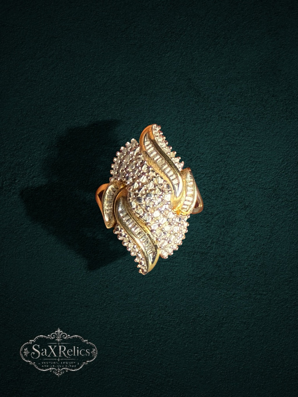 My Store SAXRelics ornate gold statement ring with brilliant and baguette-cut stones on a dark textured background