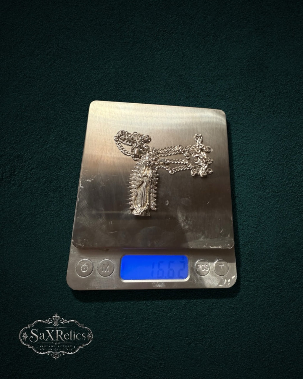 My Store SaxRelics silver-tone Our Lady of Guadalupe pendant necklace with curb chain on a digital scale